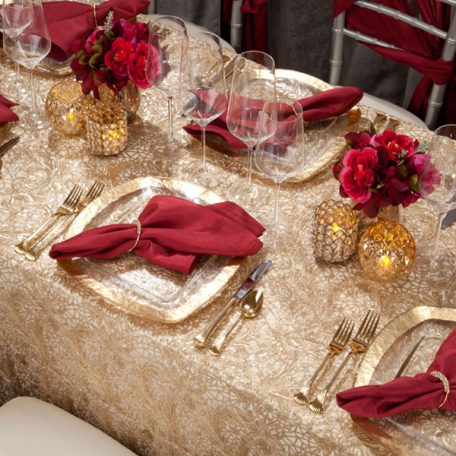 Golden Helena Beaded overlay shown over an ivory Shantung Table Linen. Topped off with our Ice Square with Gold Rim Charger and a Merlot Shantung Napkin