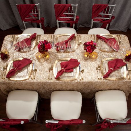 Golden Helena Beaded overlay shown over an ivory Shantung Table Linen. Topped off with our Ice Square with Gold Rim Charger and a Merlot Shantung Napkin